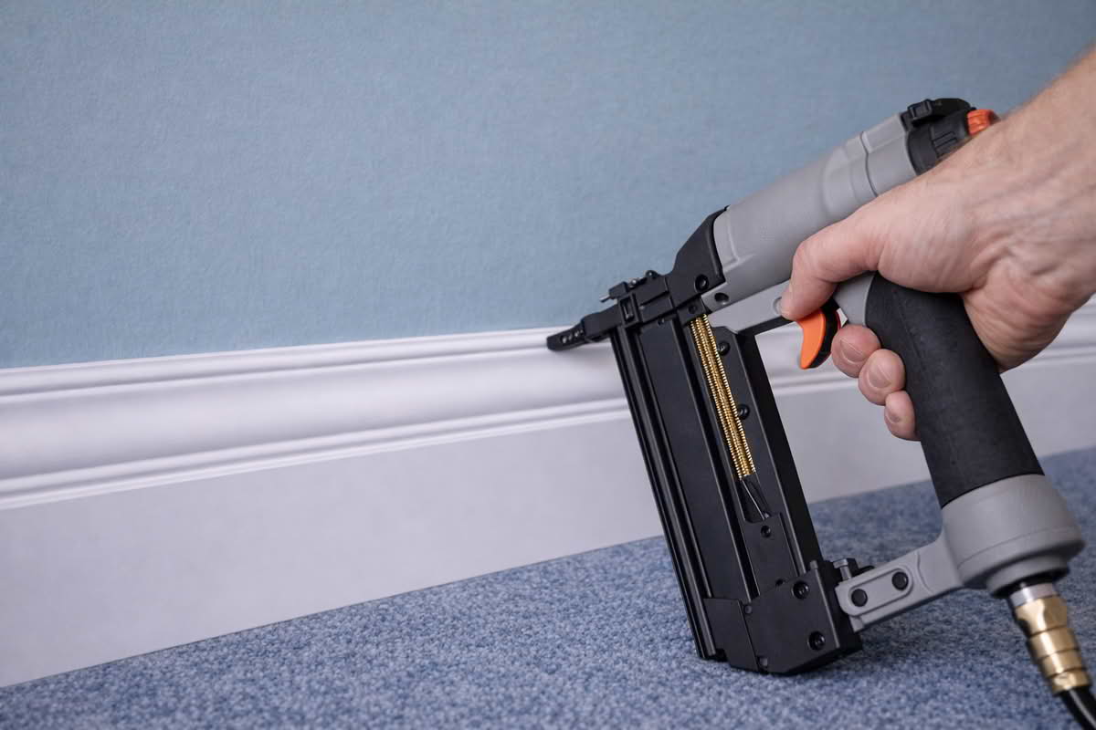 Brad nailer positioned against interior trim during finish carpentry and molding installation